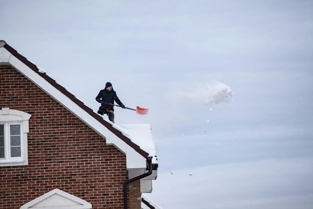 Man Removing Snow from Rooftop Using Shovel